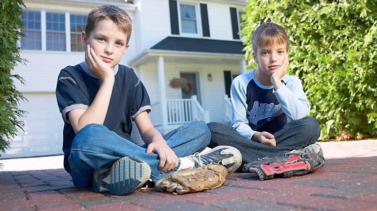 Two kids in front of a house
